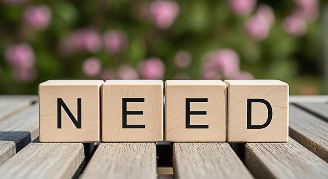 Wooden blocks spelling NEED on a weathered wooden table in a garden setting symbolizing essential requirements and the importance of fulfilling basic needs in a peaceful and natural environment photo