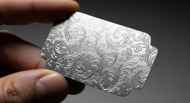 Close-up of a hand holding a detailed metal plate with intricate floral patterns, demonstrating texture and craftsmanship with a focus on design and elegance photo