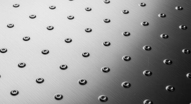 Intricate metallic surface design with evenly spaced rivets, creating a textured pattern and highlighting geometric precision and industrial aesthetic, a close-up view photo