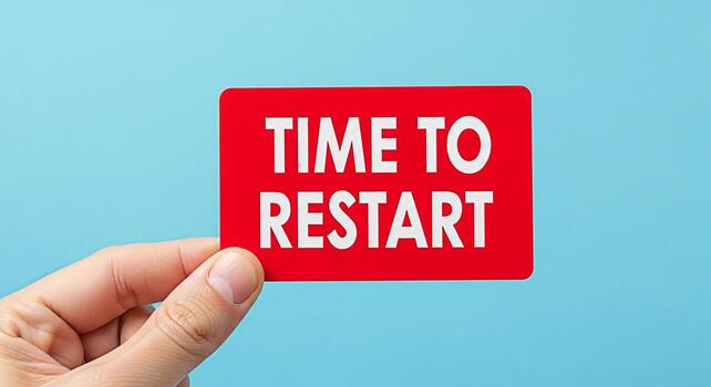 Human hand holding a red card with the message Time to Restart against a light blue background symbolizing the need for a fresh start system reboot or a new beginning conveying a sense of urgency and photo