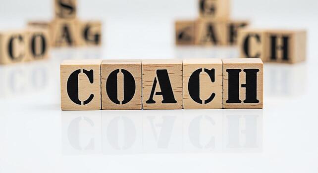 Wooden blocks spelling COACH on a reflective white surface representing guidance and mentorship conveying a sense of support and professional development in a clean and minimalist setting ideal for bu photo