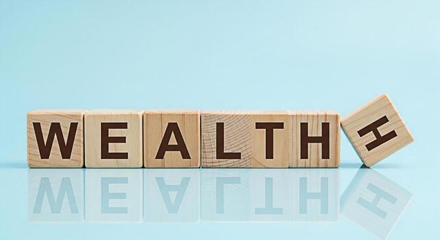 Wooden blocks spelling Wealth on a reflective surface against a light blue background symbolizing financial success investment growth and the importance of building and maintaining wealth for a secure photo