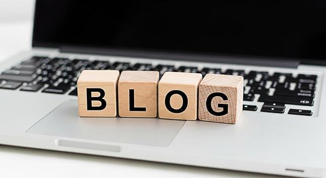 Wooden blocks spelling BLOG resting on a silver laptop keyboard in a bright modern workspace symbolizing online content creation digital marketing and the importance of blogging for business success photo