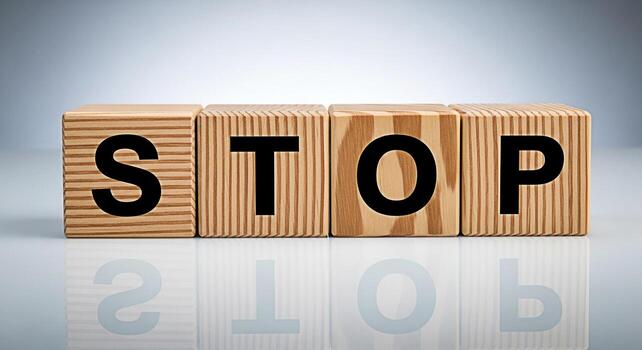 Wooden blocks spelling STOP on a reflective surface conveying a message of caution and control in a bright minimalist setting symbolizing boundaries and the importance of pausing for reflection photo
