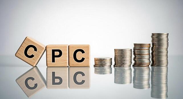 Wooden blocks spelling CPC next to stacks of coins on a reflective surface representing cost per click in a financial setting conveying concepts of online advertising costs marketing expenses and inve photo