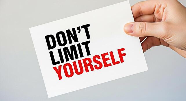 Hand holding a motivational card with the message Dont Limit Yourself in a bright studio setting promoting selfbelief and encouraging personal growth with a powerful and inspiring message photo