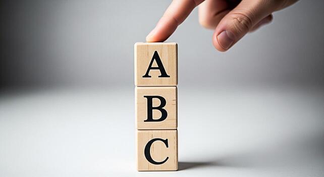 Hand pressing wooden ABC blocks in a bright studio setting symbolizing basic education learning and the foundation of knowledge with a focus on simplicity and early childhood development photo