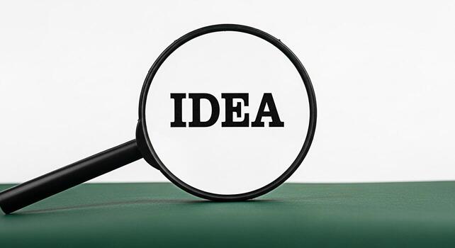 Magnifying glass focusing on the word IDEA on a green surface symbolizing discovery and innovation representing a concept of searching for solutions and creative thinking in a bright clean environment photo