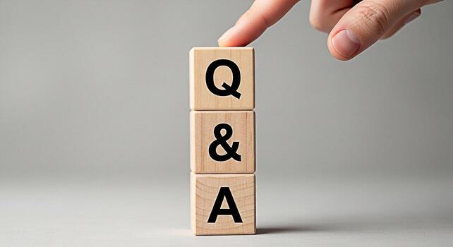 Hand gently touching wooden blocks stacked vertically with the letters QA against a neutral background symbolizing questions and answers knowledge acquisition and problemsolving with clarity photo