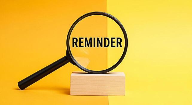 Magnifying glass focusing on the word Reminder displayed on a bright yellow background emphasizing the importance of deadlines and tasks creating a sense of urgency and focus on time management photo