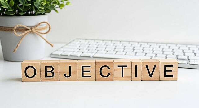 Wooden blocks spelling Objective on a white desk next to a potted plant and computer keyboard representing goal setting and a focused determined mindset in a clean modern office environment photo
