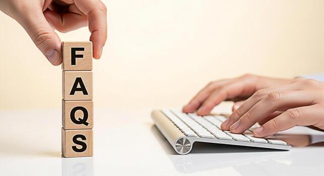 Hand arranging wooden blocks with FAQs letters on a white desk while typing on a keyboard symbolizing information access and customer support in a modern office setting conveying a sense of clarity an photo