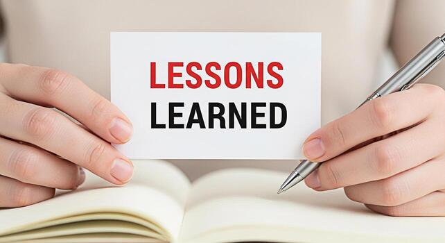 Closeup of hands holding a card with the text Lessons Learned over an open notebook symbolizing reflection and experience in a learning environment fostering a mood of growth and selfimprovement photo