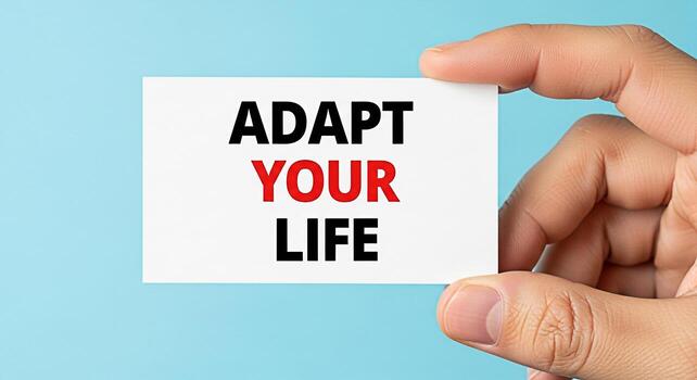 Closeup of a hand holding a card with the motivational message Adapt Your Life against a light blue background symbolizing resilience personal growth and the importance of adapting to change in a posi photo