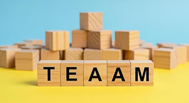 Wooden blocks spelling out TEAM on a yellow surface against a blue background symbolizing collaboration unity and the importance of teamwork in achieving success and fostering a supportive work enviro photo