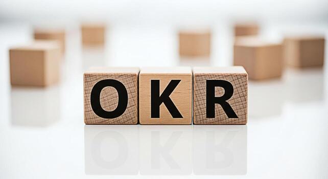 Wooden blocks displaying OKR on a white reflective surface representing Objectives and Key Results in a business setting symbolizing goal setting strategic planning and performance management for orga photo
