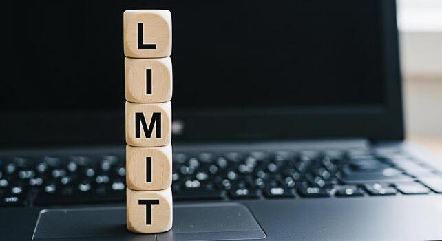 Wooden blocks spelling LIMIT stacked on a laptop keyboard symbolizing boundaries and restrictions in the digital world representing the concept of setting limits for screen time social media usage or photo