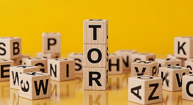 Wooden alphabet blocks spelling out TOR on a reflective surface against a bright yellow background representing education learning and the building blocks of knowledge with a playful and educational m photo