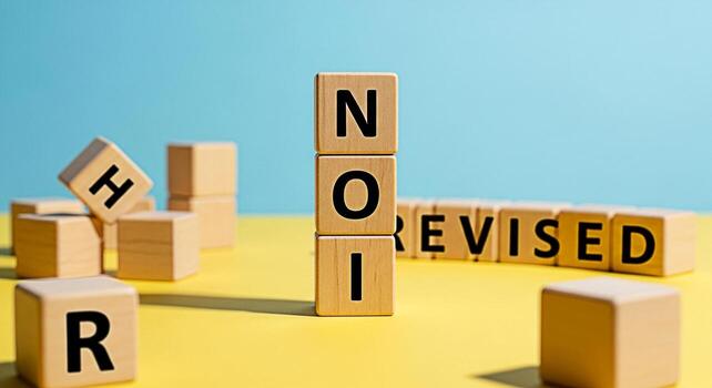 Wooden blocks spelling out NOI REVISED on a yellow surface against a blue background representing updates changes and improvements in a visually appealing and modern way conveying a sense of progress photo