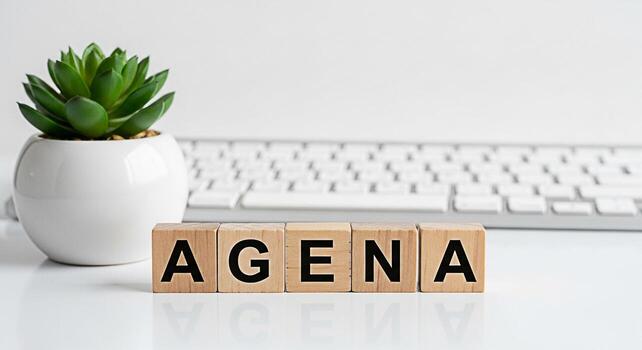 Wooden blocks spelling AGENDA on a white desk with a succulent plant and computer keyboard representing planning and organization in a modern office environment for productivity and efficiency photo