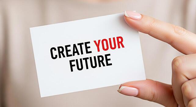 Closeup of a manicured hand holding a white card with the motivational message Create Your Future in bold letters promoting a positive and proactive mindset in a neutral encouraging setting photo