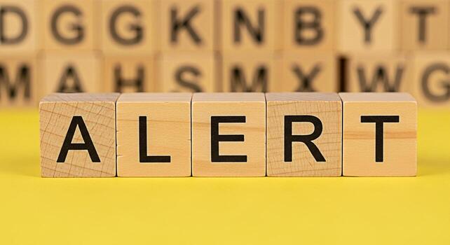 Wooden blocks spelling ALERT on a yellow surface conveying a sense of urgency and importance with blurred background blocks adding depth suitable for warnings notifications and important announcements photo