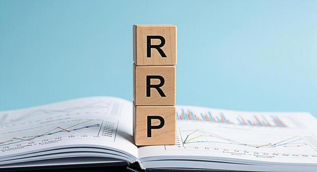 Wooden blocks displaying RRP resting on an open book filled with colorful financial charts against a light blue background representing retail price strategy and business growth analysis with a focus photo