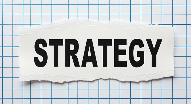 Bold Strategy text displayed on a torn piece of paper placed on a blue grid background symbolizing planning and strategic thinking for business success and effective problemsolving in a structured env photo