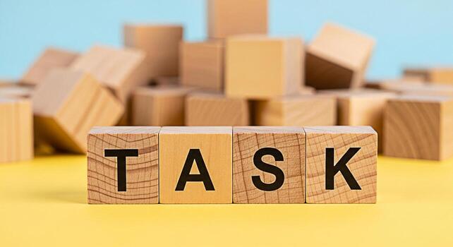 Wooden blocks spelling TASK on a yellow surface representing project management and workload in a bright minimalist setting conveying a sense of focus and organization for business and productivity co photo