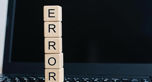 Stack of wooden blocks spelling ERROR in front of a laptop screen symbolizing technical difficulties system failure or software malfunction creating a sense of frustration and the need for troubleshoo photo