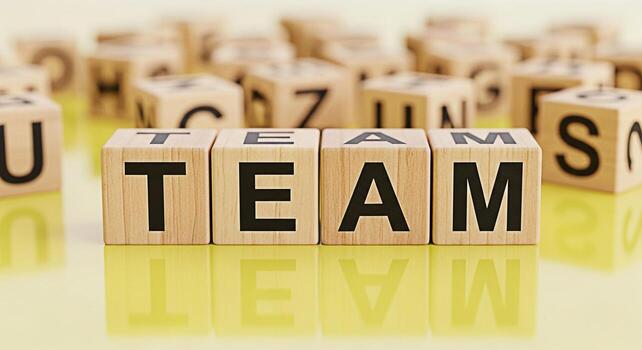 de madera bloques ortografía equipo en un reflexivo amarillo superficie rodeado por otro letrado bloques simbolizando colaboración unidad y el importancia de trabajo en equipo en lograr común metas en un brillante envi foto