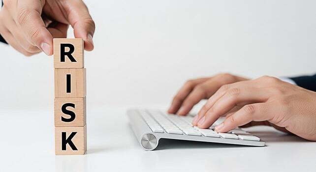 Professional placing wooden blocks spelling RISK on a white desk while typing on a keyboard symbolizing calculated risktaking and strategic decisionmaking in a modern business environment conveying a photo