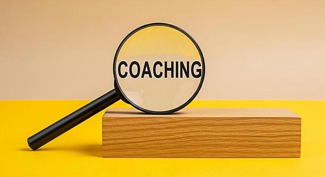 Magnifying glass focusing on the word Coaching resting on a wooden block in a studio setting symbolizing guidance mentorship and the process of personal or professional development for success photo