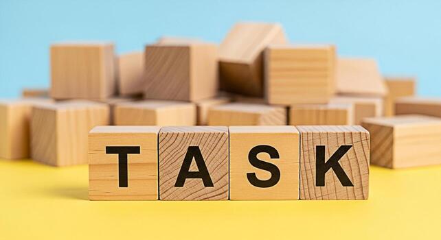 Wooden blocks spelling TASK on a yellow surface with a light blue background representing a challenge or assignment conveying a sense of focus determination and the importance of completing objectives photo
