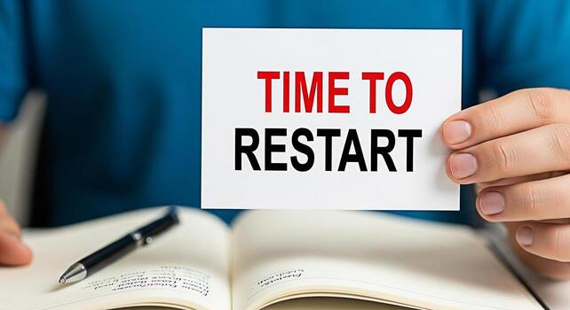 Closeup of a hand holding a card with the words Time to Restart over an open notebook with a pen symbolizing a fresh start new beginnings and the need for change in a business or personal project photo