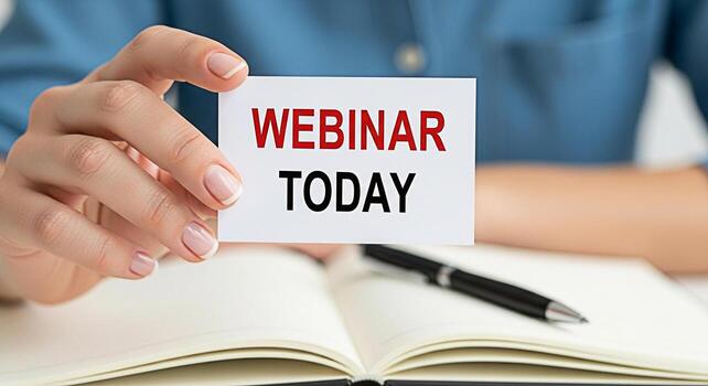 Woman holding a card with the words Webinar Today over an open notebook emphasizing the importance of online learning and timely information in a professional and organized setting creating a sense of photo
