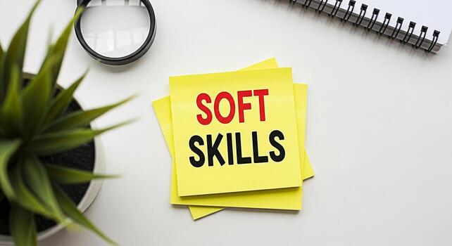 Yellow sticky notes displaying Soft Skills on a bright white desk surrounded by a magnifying glass a potted plant and a notebook emphasizing the importance of interpersonal abilities in a professional photo