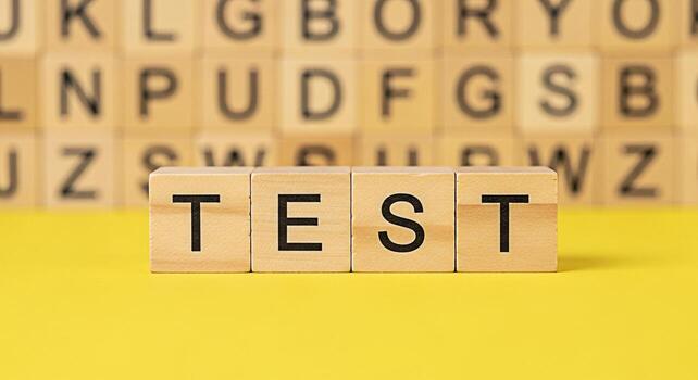 Wooden blocks spelling TEST on a bright yellow surface with blurred alphabet blocks in the background conveying the concept of examination assessment and the importance of preparation and knowledge photo