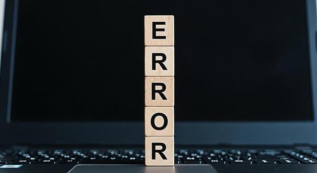 Wooden blocks spelling ERROR stand on a laptop keyboard symbolizing a system failure software bug or technical problem in a modern digital environment creating a sense of frustration and urgency photo