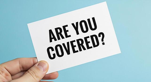 Hand holding a card with the question Are You Covered against a light blue background representing insurance coverage and financial security creating a sense of reassurance and protection photo