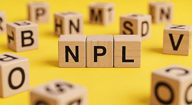Wooden blocks spelling NPL on a yellow surface representing nonperforming loans and financial challenges creating a serious and concerning mood about debt and economic issues in a studio setting photo