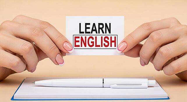 elegante manos participación un tarjeta con el texto aprender Inglés encima un cuaderno y bolígrafo en un beige antecedentes simbolizando educación idioma adquisición y el búsqueda de conocimiento con un limpiar y moderno foto