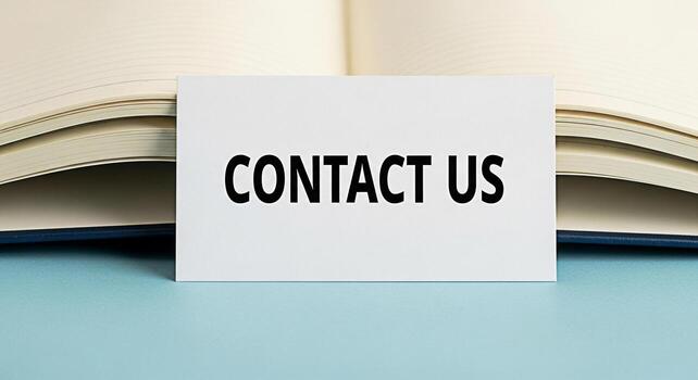 A white card displaying Contact Us placed in front of an open notebook on a light blue surface symbolizing communication and customer service for business inquiries and support fostering a sense of co photo