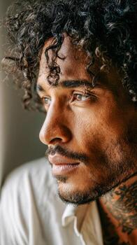 Young man with curly hair enjoys a moment of reflection in soft light photo