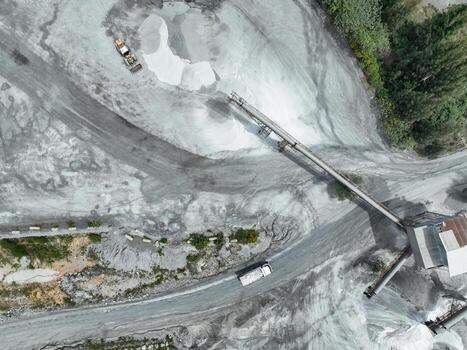 Granite and limestone crushing plant with dump trucks and excavators processing raw stone into construction aggregate for concrete and infrastructure development. Stone mill factory. photo