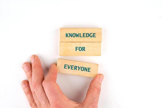 Learning for Everyone concept. Words KNOWLEDGE FOR EVERYONE made from blocks by hand on a light background, top view photo