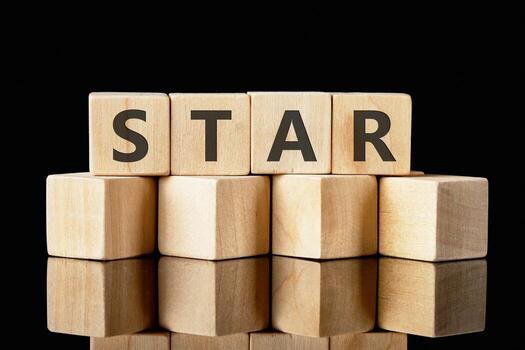 Wooden blocks arranged to form the word star sit on a reflective surface, creating an eye-catching visual against a dark background, emphasizing simplicity photo