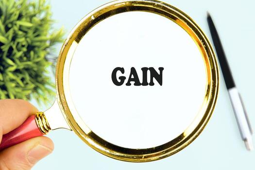 aumentador vaso retenida por un mano se enfoca en el negrita palabra ganancia en contra un ligero fondo, destacando el importancia de crecimiento y comprensión en varios contextos foto