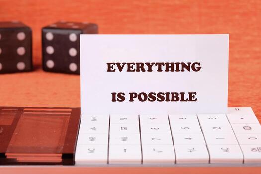 Business anything possible concept. Copy space. Text EVERYTHING IS POSSIBLE on a business card with game cubes in the background and a calculator in the foreground photo