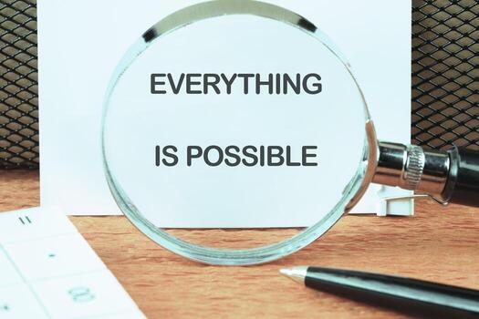 Business anything possible concept. Copy space. Text EVERYTHING IS POSSIBLE focused on the notebook through a magnifying glass photo